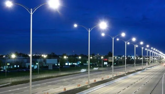 Via pública iluminada por postes com braços duplos, exemplo de projeto de iluminação